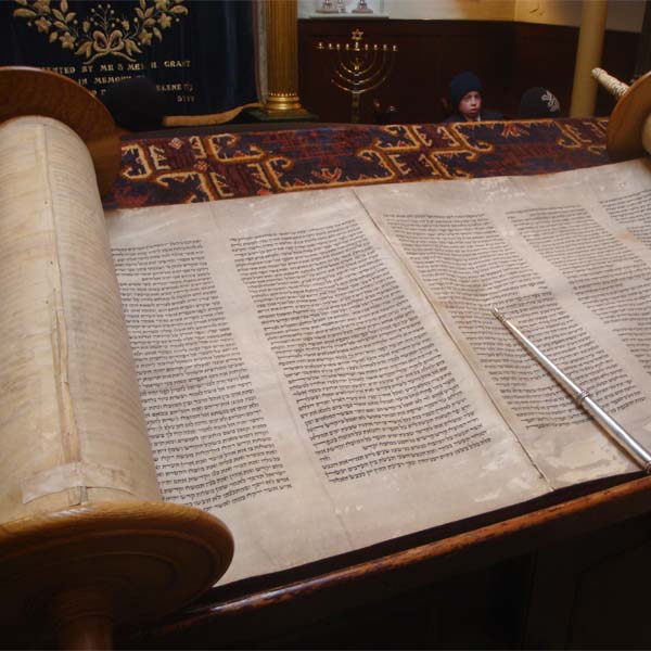 Close up of a Torah Scroll with a yad laying on it